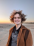 Person with curly hair standing on a beach